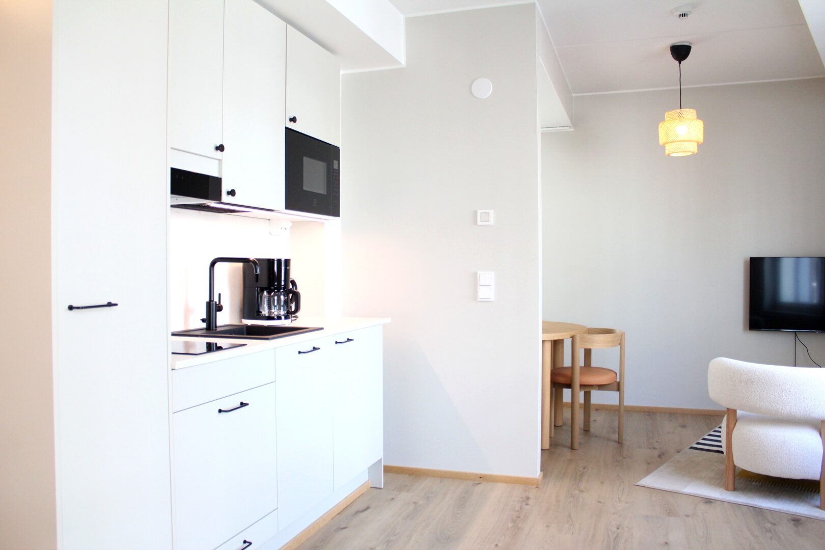 Bright modern kitchen with white cabinets, black coffee maker on the counter, and a built-in microwave above.
